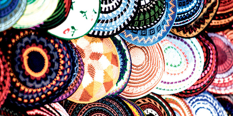 A vibrant display of round, woven baskets with intricate, colorful geometric and floral patterns stacked closely together makes the case for Canadian-Jewish exceptionalism in artistry and cultural expression.