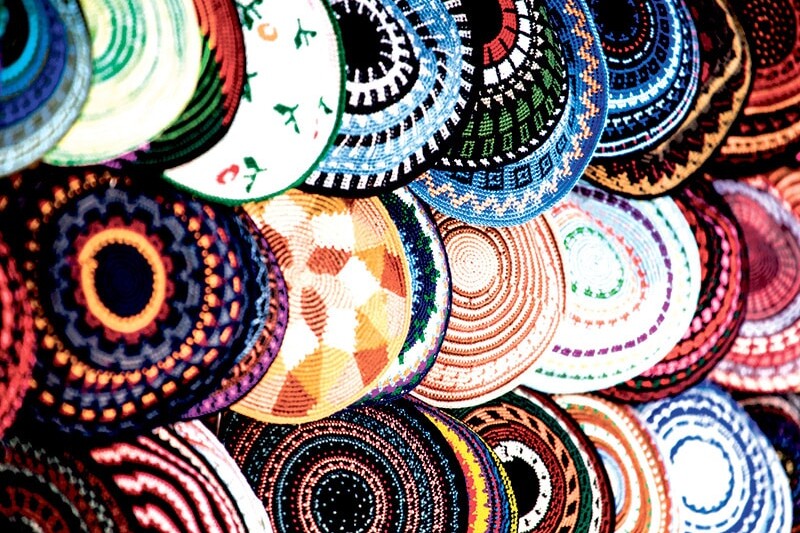 A vibrant display of round, woven baskets with intricate, colorful geometric and floral patterns stacked closely together makes the case for Canadian-Jewish exceptionalism in artistry and cultural expression.