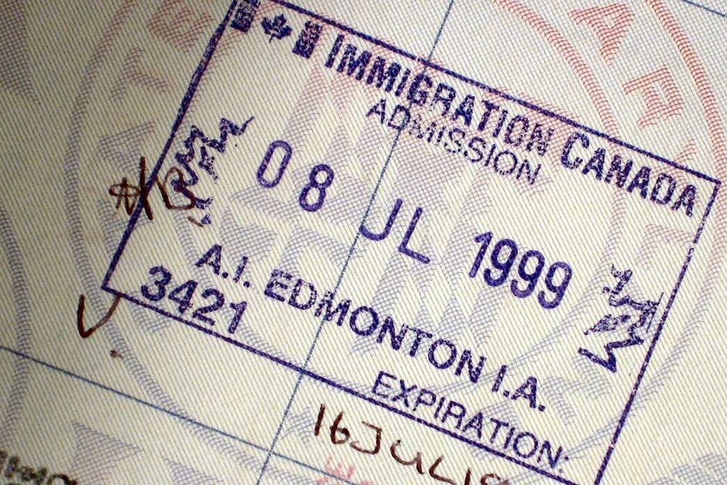 A close-up of a Canada immigration admission stamp in a passport, dated 8 July 1999, showing entry at Edmonton, Alberta, with handwritten marks and text in English and another script.