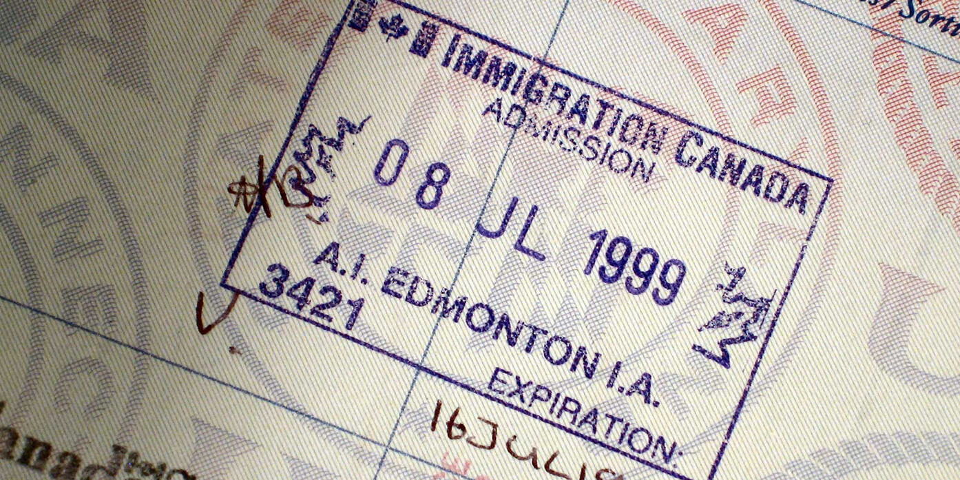 A close-up of a Canada immigration admission stamp in a passport, dated 8 July 1999, showing entry at Edmonton, Alberta, with handwritten marks and text in English and another script.