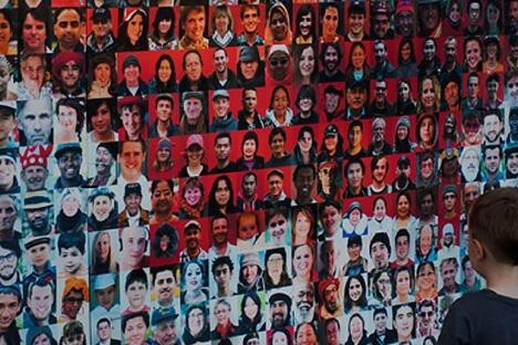 A young boy stands before a wall filled with hundreds of faces in a grid, showcasing the diversity of ages, genders, and ethnicities—reflecting intercultural relations and adaptation in Canada amid contact and discrimination.